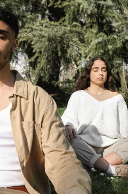 Peaceful scene of a couple meditating outdoors, embracing relaxation and tranquility.